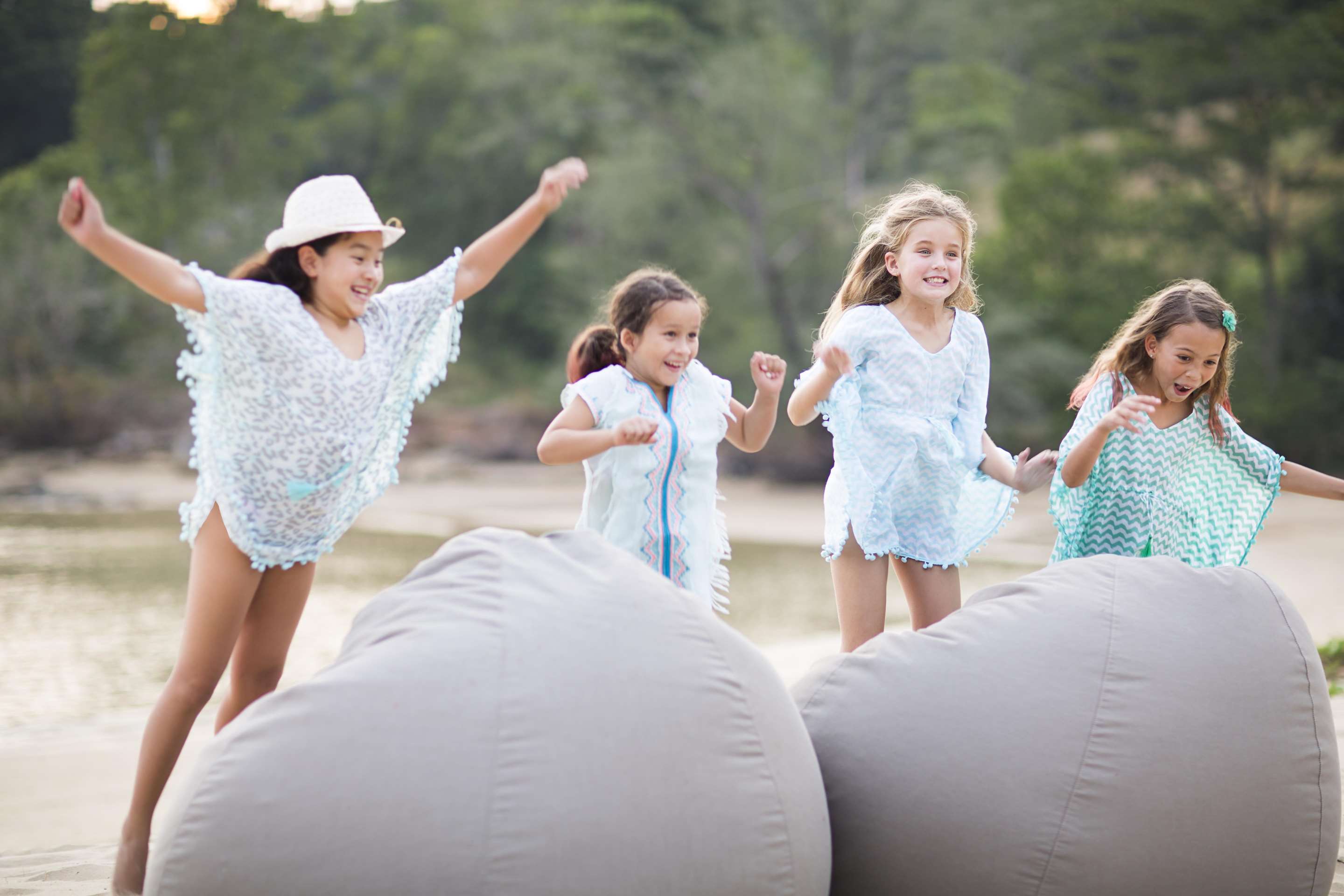 Four children jumping onto cosy beanbags on the beach