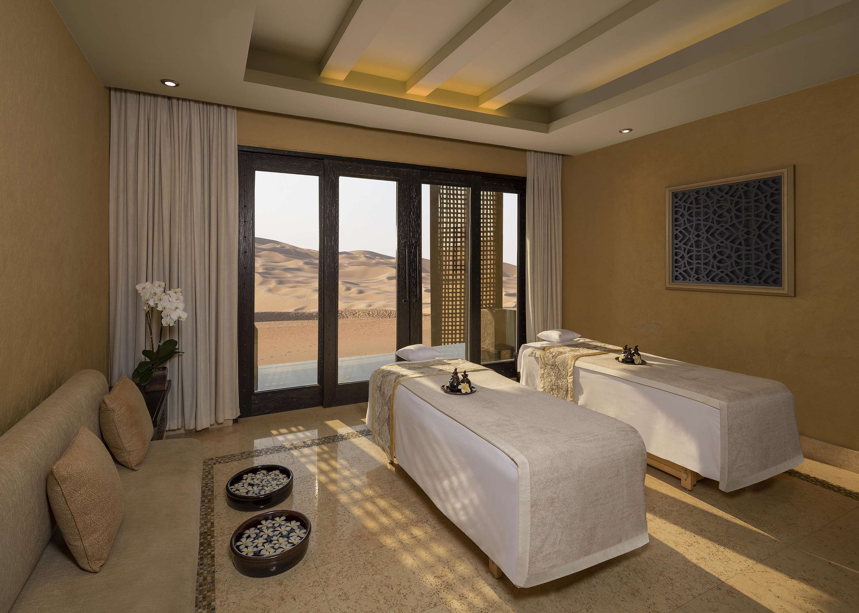 Interior view of spa treatment room with setup for couple and desert dune view